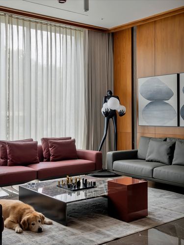 Living room with maroon and grey sofas, sculptural lamp, and a dog resting on the rug