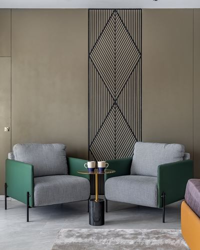 Two green and houndstooth armchairs flank a round marble side table under a diamond metal wall panel