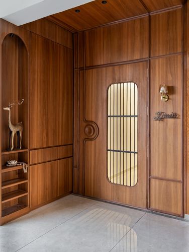 Wood-panelled entryway with arched niche, deer statue, and glass-paned front door