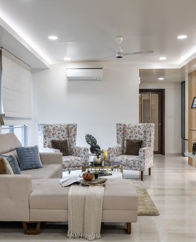 Beige living room with floral wingback chairs, sectional sofa, and cove-lit ceiling