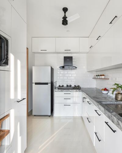 White galley kitchen with black handles, subway tile backsplash and speckled stone countertop