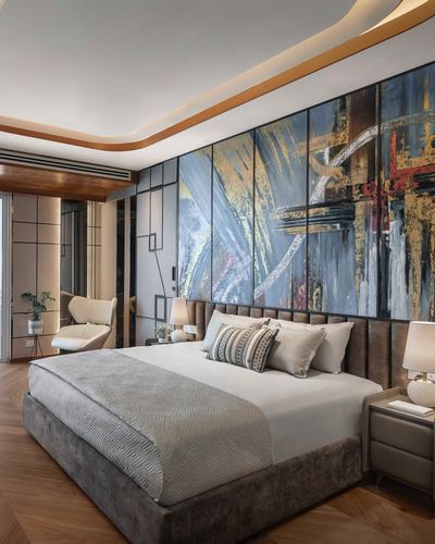 Bedroom with upholstered brown bed, gold-trimmed cove ceiling, and large abstract art panel on wall