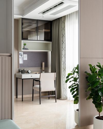 Small study nook with desk, chair, pinboard, and glass cabinet framed by fluted panel doorway