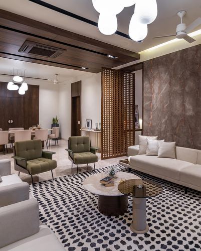 Living room with jali screen divider, marble wall, olive armchairs and patterned rug