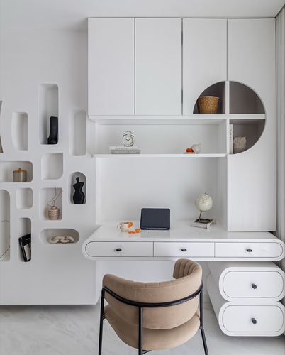 White study nook with sculptural wall niches, rounded desk drawers and a beige velvet chair