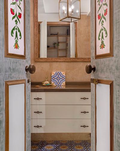 Painted double doors open into a bathroom vanity with mirror and pendant chandelier beyond