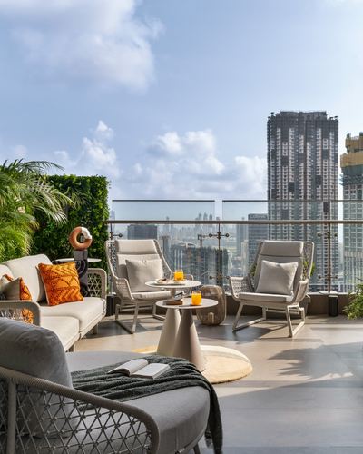 Rooftop terrace lounge with rope chairs, round tables, and city skyline view