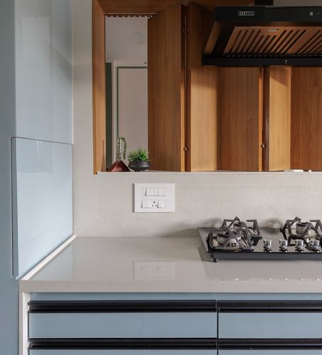 Kitchen counter with gas hob, stone backsplash, and wooden louvered shutters concealing chimney hood