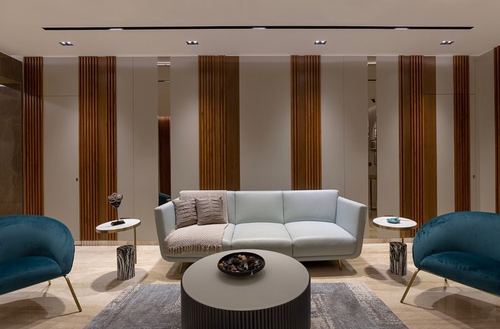 Living room with pale sofa, teal velvet chairs, and fluted wood-and-mirror panelled wall