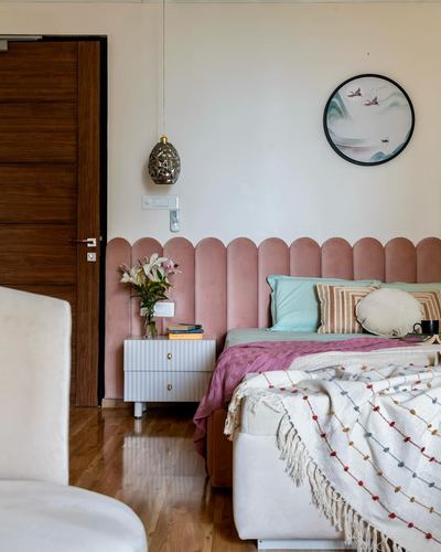 Bedroom with scalloped pink velvet headboard, round bird mirror, and wooden door