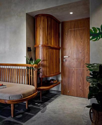 Entryway with wood-grain door, curved wood cabinet niche, slatted bench, and plants