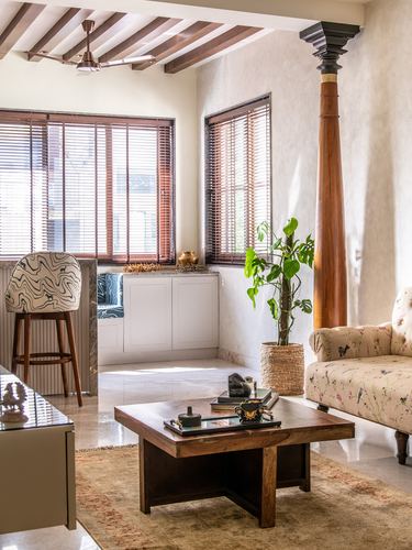Living room with carved wooden pillar, floral settee, wooden beamed ceiling and window seat