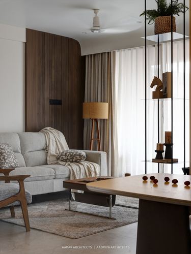 Living room with curved wood wall, beige sofa, floor lamp, and hanging glass display shelf