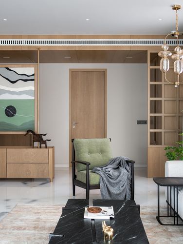 Living room with wood paneling, green armchair, black marble coffee table, and glass-fronted cabinet