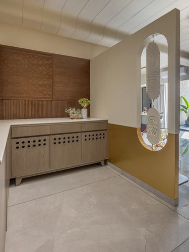 Entry foyer with carved wood panel, wooden sideboard, and mustard partition wall with oval mirror cutout