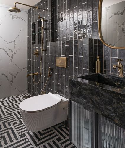 Bathroom with black ribbed tile walls, marble shower wall, brass fixtures, and dark stone vanity