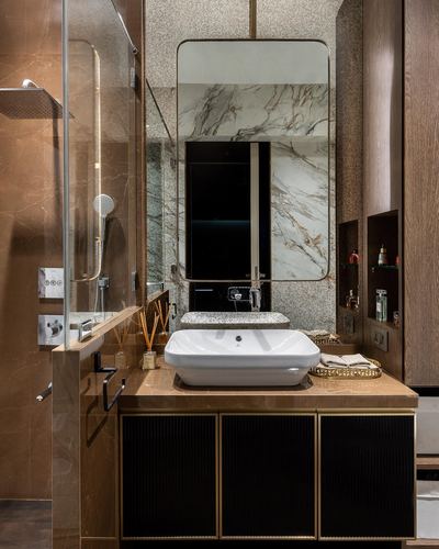 Bathroom vanity with white vessel sink, marble mirror panel, and fluted black-gold cabinetry