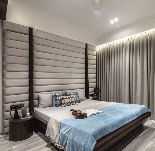 Bedroom with grey channel-tufted headboard wall, wooden bed, blue throw, violin and book on it
