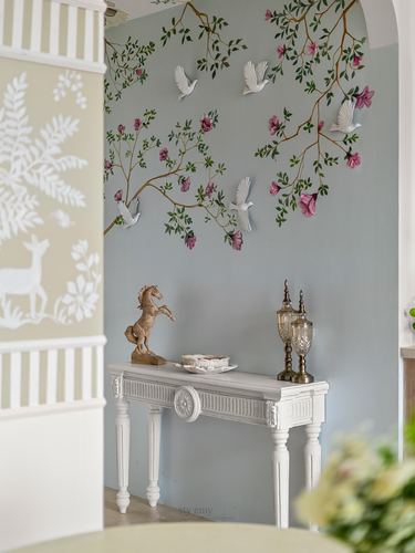 Foyer with chinoiserie floral mural, white bird sculptures, and carved white console table