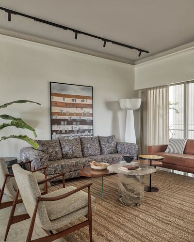 Living room with patterned sofa, cane-armed chairs, sculptural lamp and stone coffee table