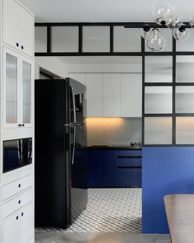 Kitchen with navy blue cabinetry, black fridge, herringbone backsplash and glass crittall partition