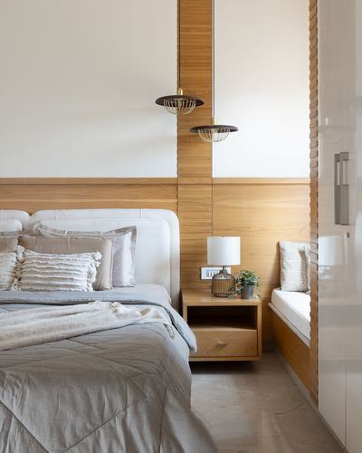 Bedroom with upholstered headboard, wood-panelled wall, twin pendant lights and built-in window seat
