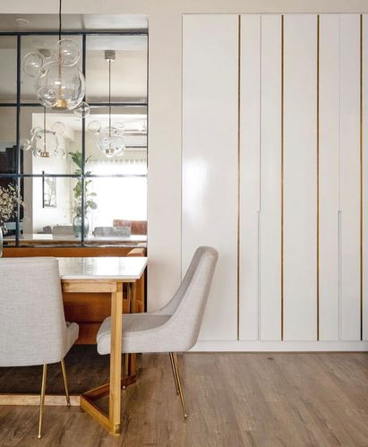 Dining nook with marble-top table, grey chairs, and gold-lined wardrobe wall