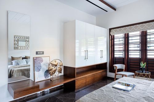 White bedroom with glossy wardrobe, floating wood console, mirror, and louvered window