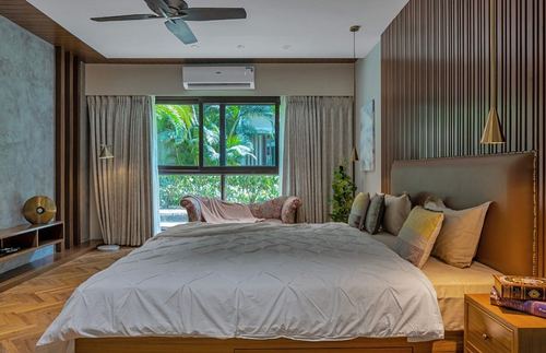 Bedroom with fluted wood wall, upholstered headboard, garden-facing window and patterned bench