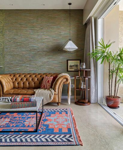 Living room with tan leather chesterfield sofa, layered kilim rugs, and tiered wooden side table