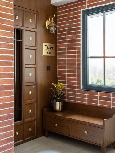 Entryway foyer with red brick wall, wooden paneled wardrobe, brass nameplate, and window bench