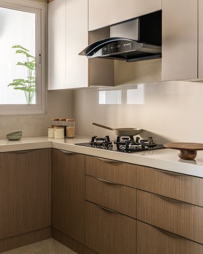 L-shaped kitchen with wood cabinetry, stone counter, black hob and steel chimney hood