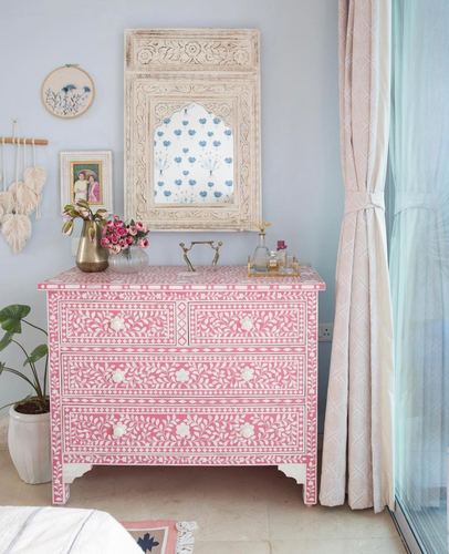 Pink and white bone-inlay dresser under a carved arched mirror against a pale blue wall