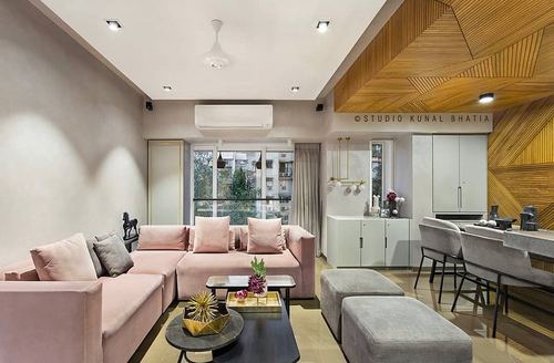 Living and dining space with pink sectional sofa and geometric wood-clad wall panel