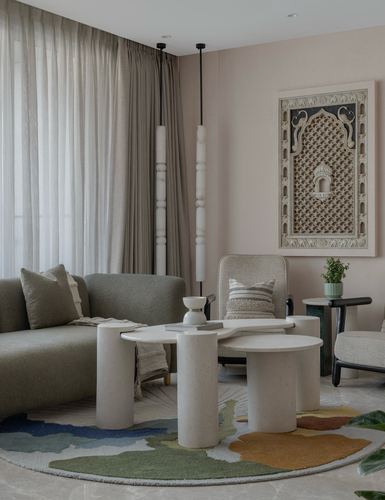 Living room with olive sofa, sculptural stone tables, and framed Indian textile art