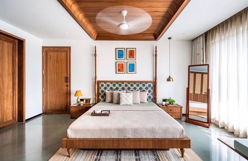 Bedroom with wood-paneled coffered ceiling, four-poster bed, patterned headboard, and standing mirror