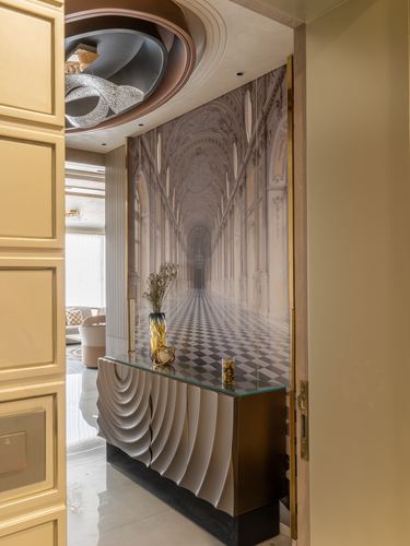 Foyer with fluted gold console beneath a mural of a grand marble corridor and sculptural ceiling light