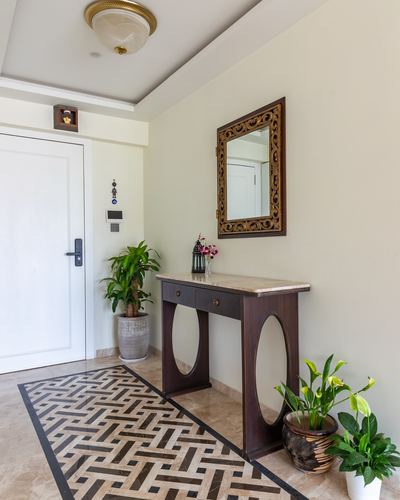 Entry foyer with carved mirror, console table, patterned marble floor and potted plants