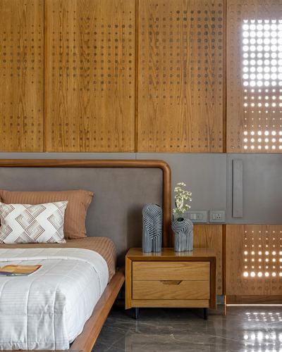 Bedroom with curved leather headboard, wooden nightstand, and perforated wood panel wall glowing with light