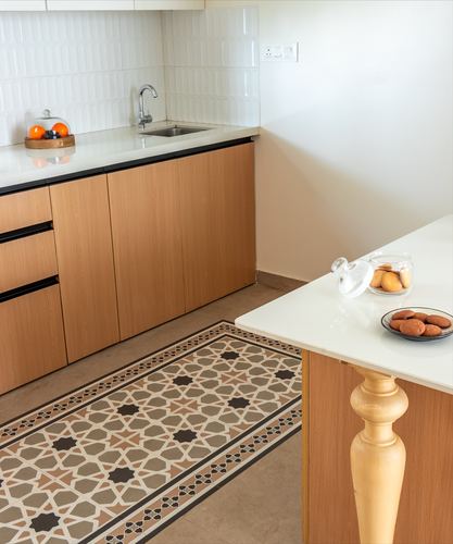 Kitchen with wood cabinetry, white counters, and a patterned tile floor runner