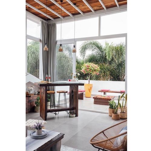Terrace lounge with reclaimed wood console table, glass walls, and lush greenery view