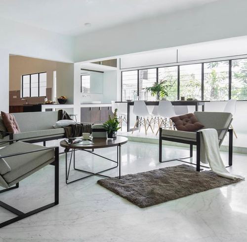 Open-plan minimalist living room with black-framed sofas, round coffee table and floor-to-ceiling windows