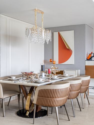 Dining room with marble table, ribbed leather chairs, crystal chandelier and orange abstract art
