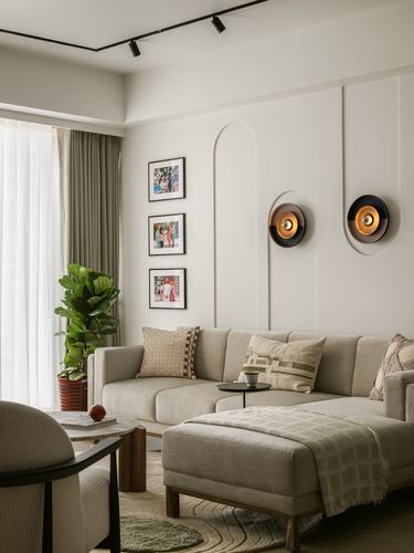 Beige sectional sofa beneath framed photos and round wall sconces in minimalist living room