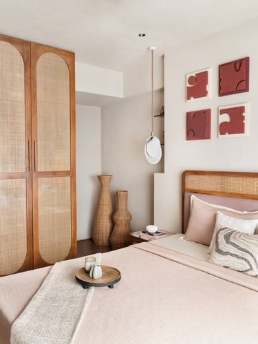 Bedroom with arched cane wardrobe, woven vases, and red relief art above cane headboard bed