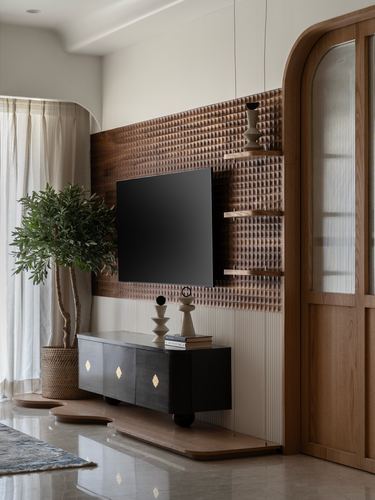 Living room with textured wood-panelled TV wall, black console, arched fluted glass door and potted plant