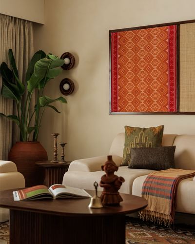 Living room corner with framed ikat textile art, terracotta vase and carved wooden figurine