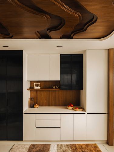 Kitchen with wavy carved wood ceiling, fluted black cabinets, and open wood display niche with fruit bowls