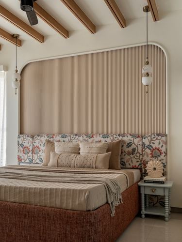 Bedroom with arched fluted headboard, floral bolsters, pendant lights and exposed wood-beam ceiling
