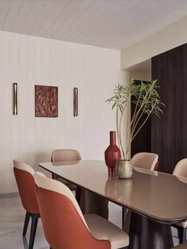 Dining room with oval table, terracotta and beige chairs, and marble floor